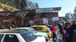 Kolombiya ve Ekvador arasındaki Rumichaca sınırında, üzerinde "Migración Colombia - Rumichaca" yazan büyük beyaz bir tabelanın bulunduğu hareketli açık hava göçmenlik kontrol noktası.