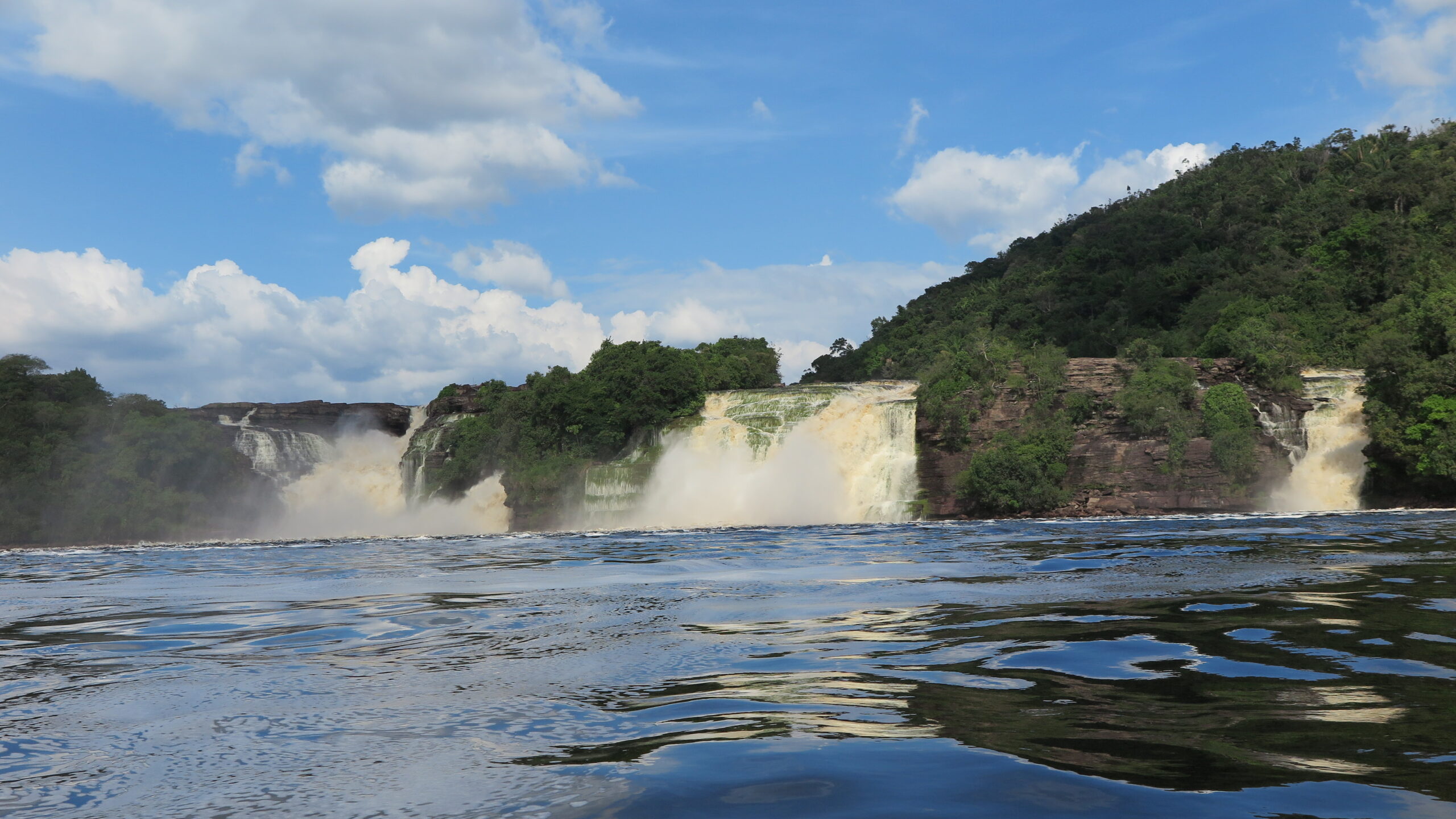 A powerful waterfall with roaring water, photographed from a boat on the river in Canaima, Venezuela