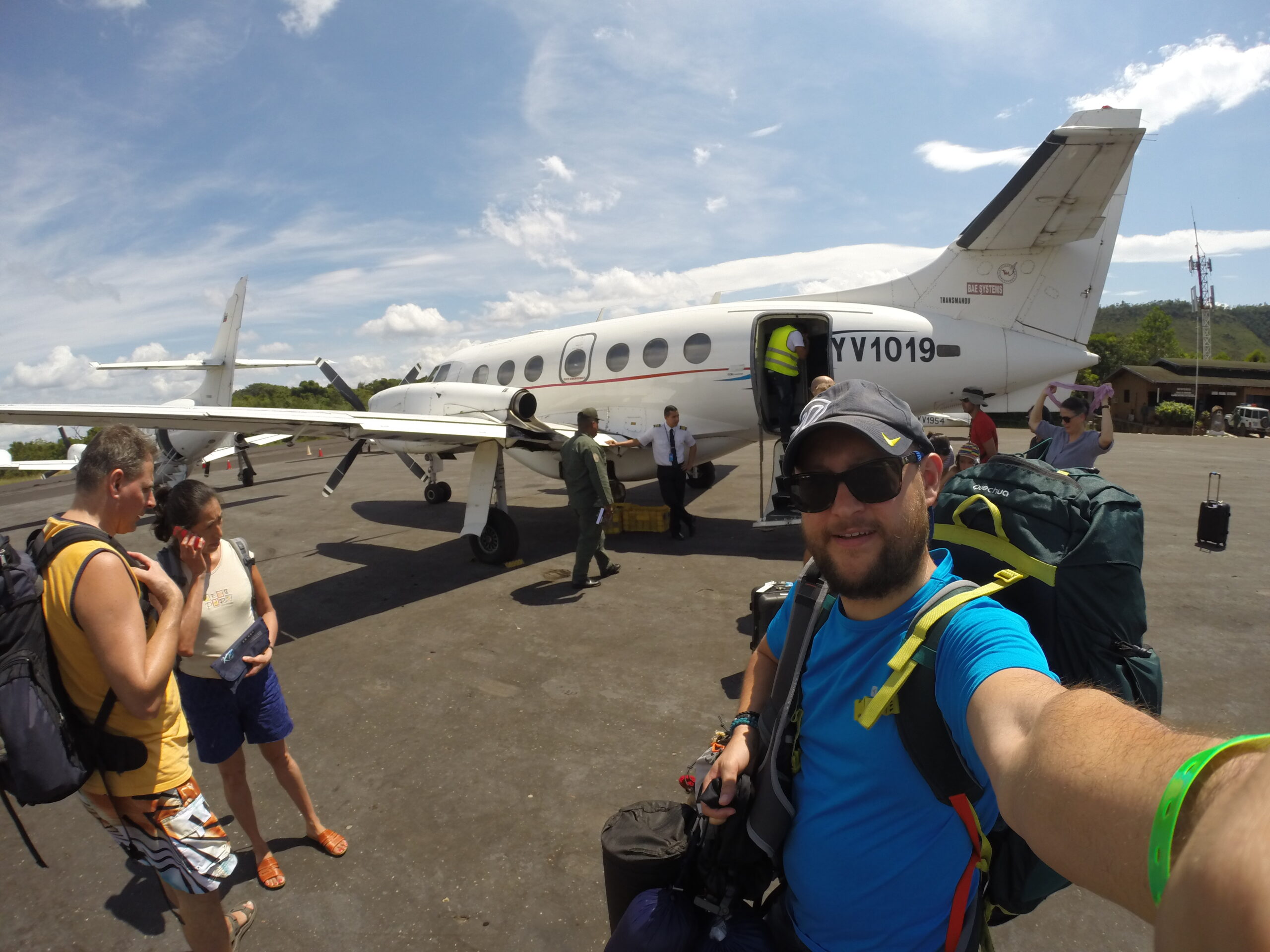 A selfie taken in front of a small plane in Canaima, Venezuela, with passengers disembarking in the background