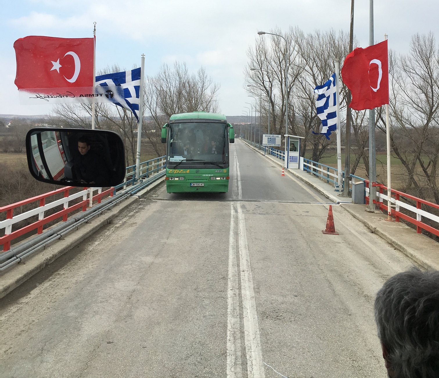 View from a bus of the border bridge between Türkiye and Greece, with both national flags visible.