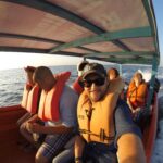 Passengers wearing life jackets on a small boat ride from Higuerote to La Tortuga Island, Venezuela, with ocean waves in the background.