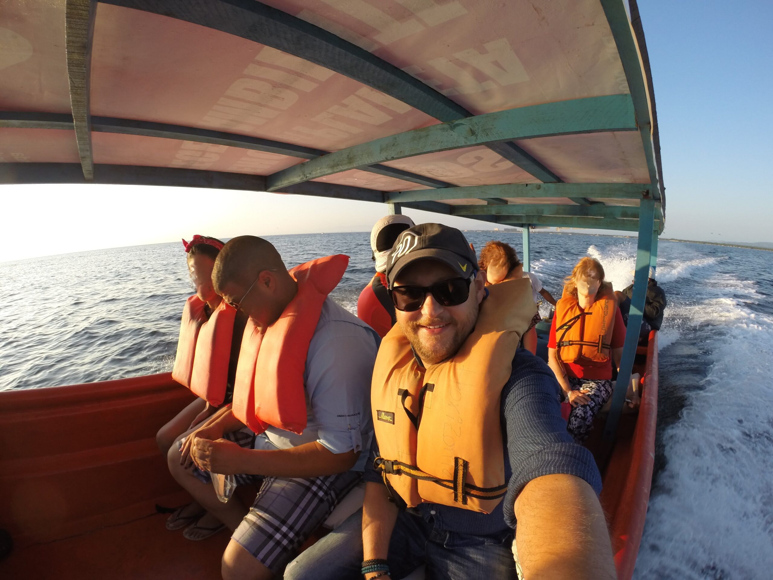 Passengers wearing life jackets on a small boat ride from Higuerote to La Tortuga Island, Venezuela, with ocean waves in the background.