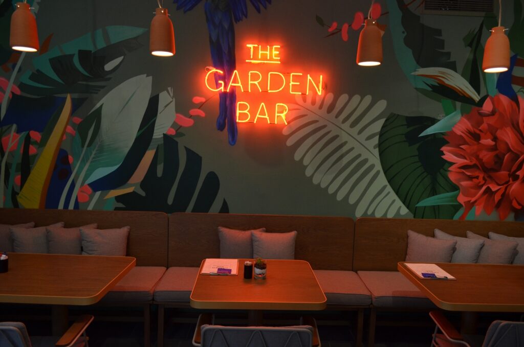 Colors Urban Hotel Selanik'teki The Garden Bar'da turuncu neon “THE GARDEN BAR” tabelası