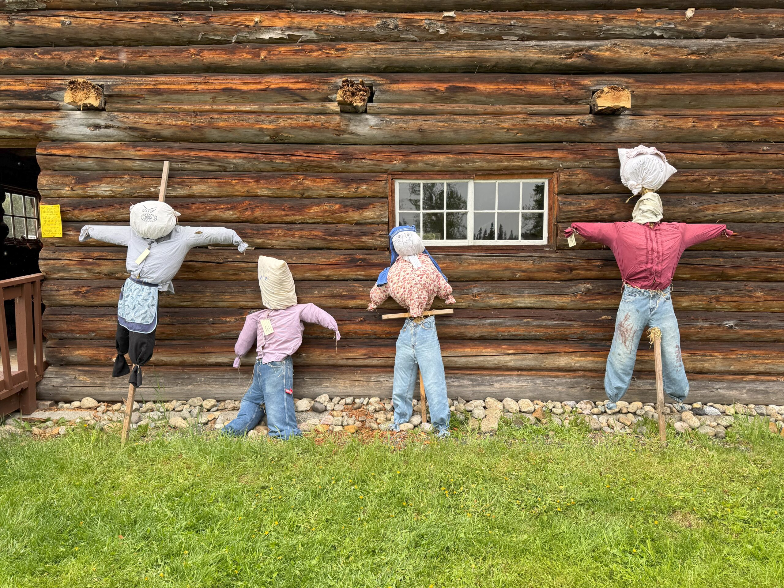 A historic animal barn at Huble Homestead with four scarecrows standing in front.