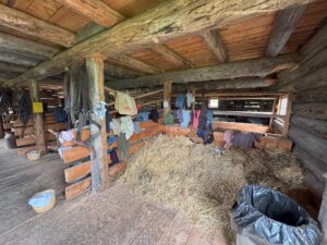 Interior of the barn at Huble Homestead with vintage tools, work clothes, and farming equipment.
