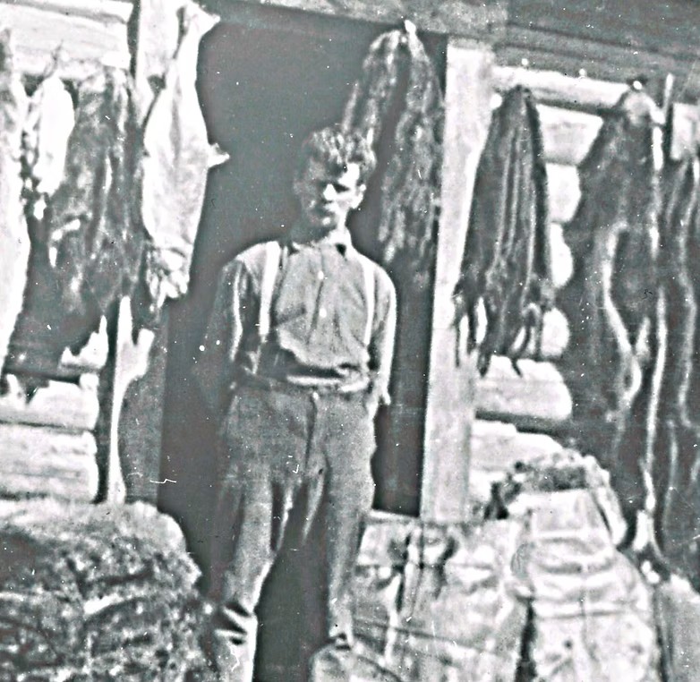 Black and white photo of Edward Seebach standing in front of a wooden building with fish and goods displayed.
