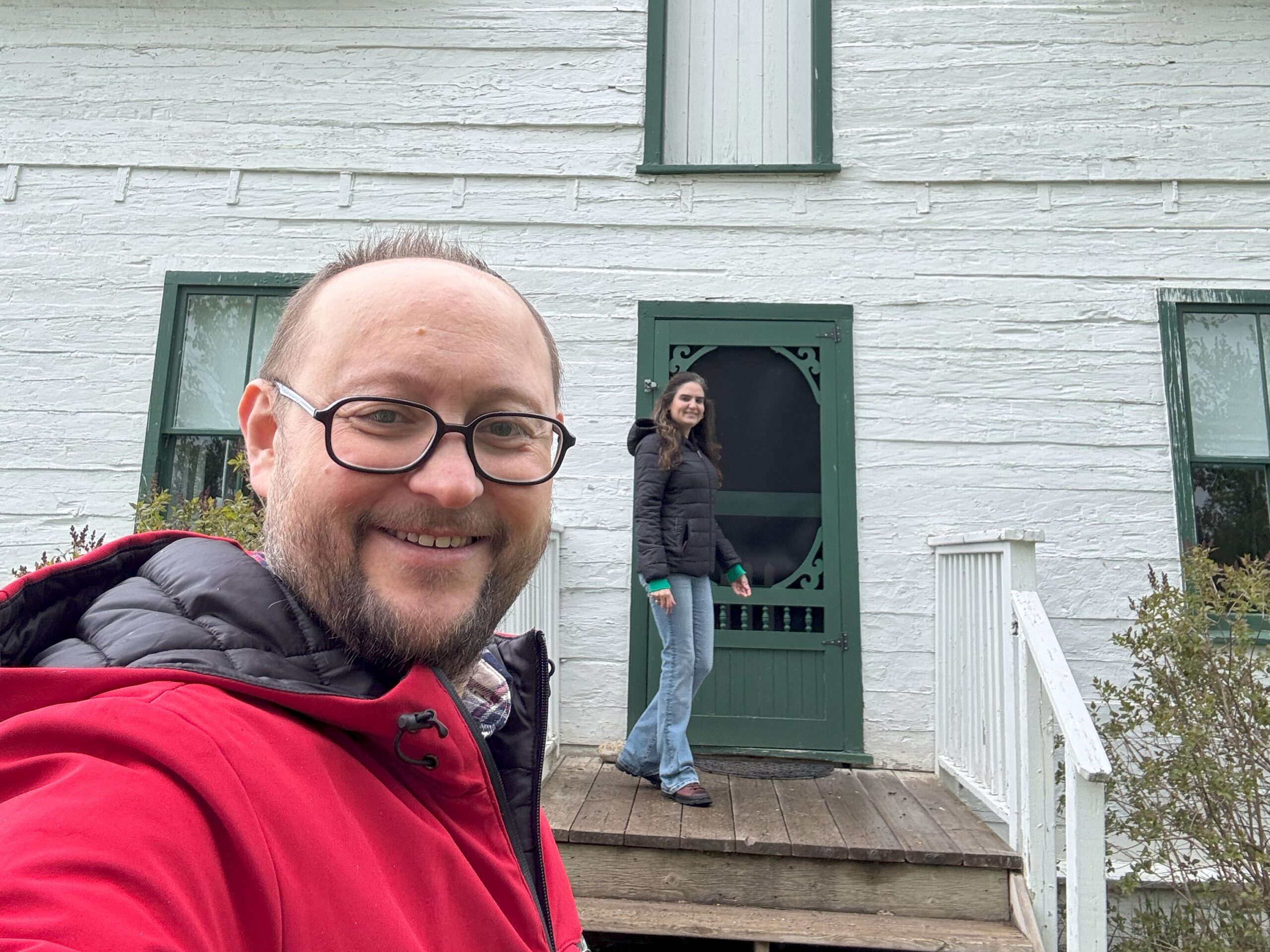 A selfie of two visitors standing in front of the historic Huble House.