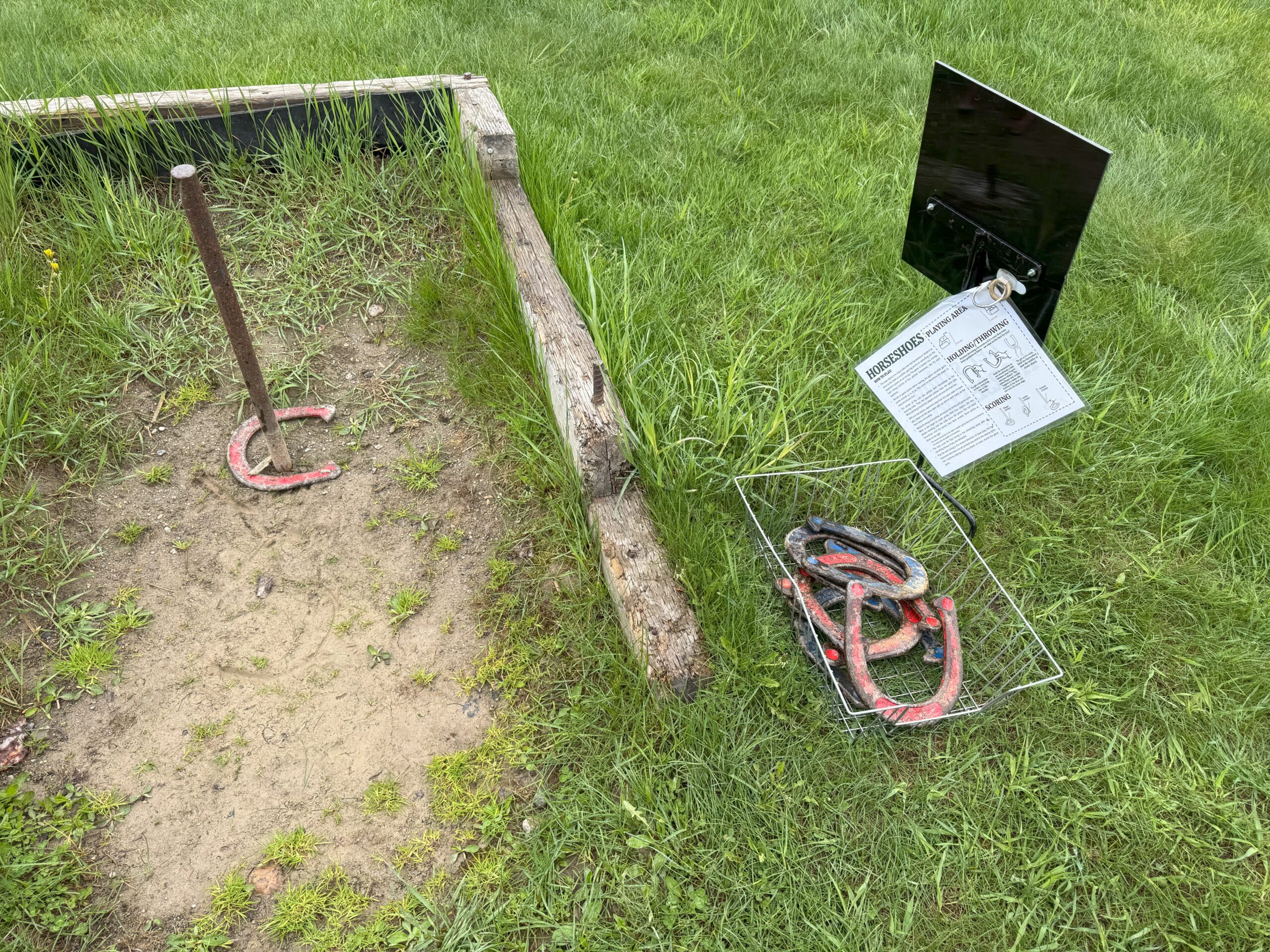 Horseshoes game setup with metal stakes and horseshoes on the grass at Huble Homestead.