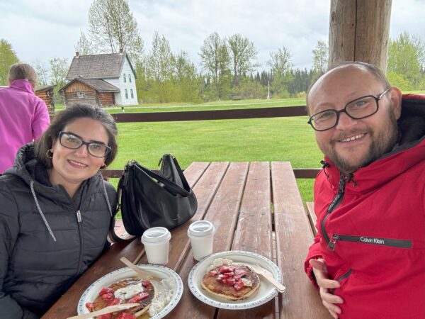 Selfie of people enjoying pancakes with strawberries for breakfast under the picnic shelter