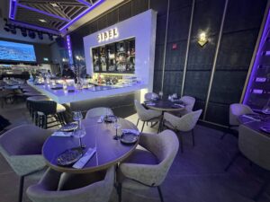 Stylish restaurant bar with modern lighting, marble counter, and surrounding tables set for guests.