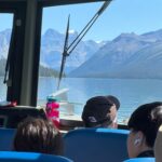 View of Maligne Lake and surrounding mountains from inside a tour boat in Jasper National Park, with passengers enjoying the scenic ride.