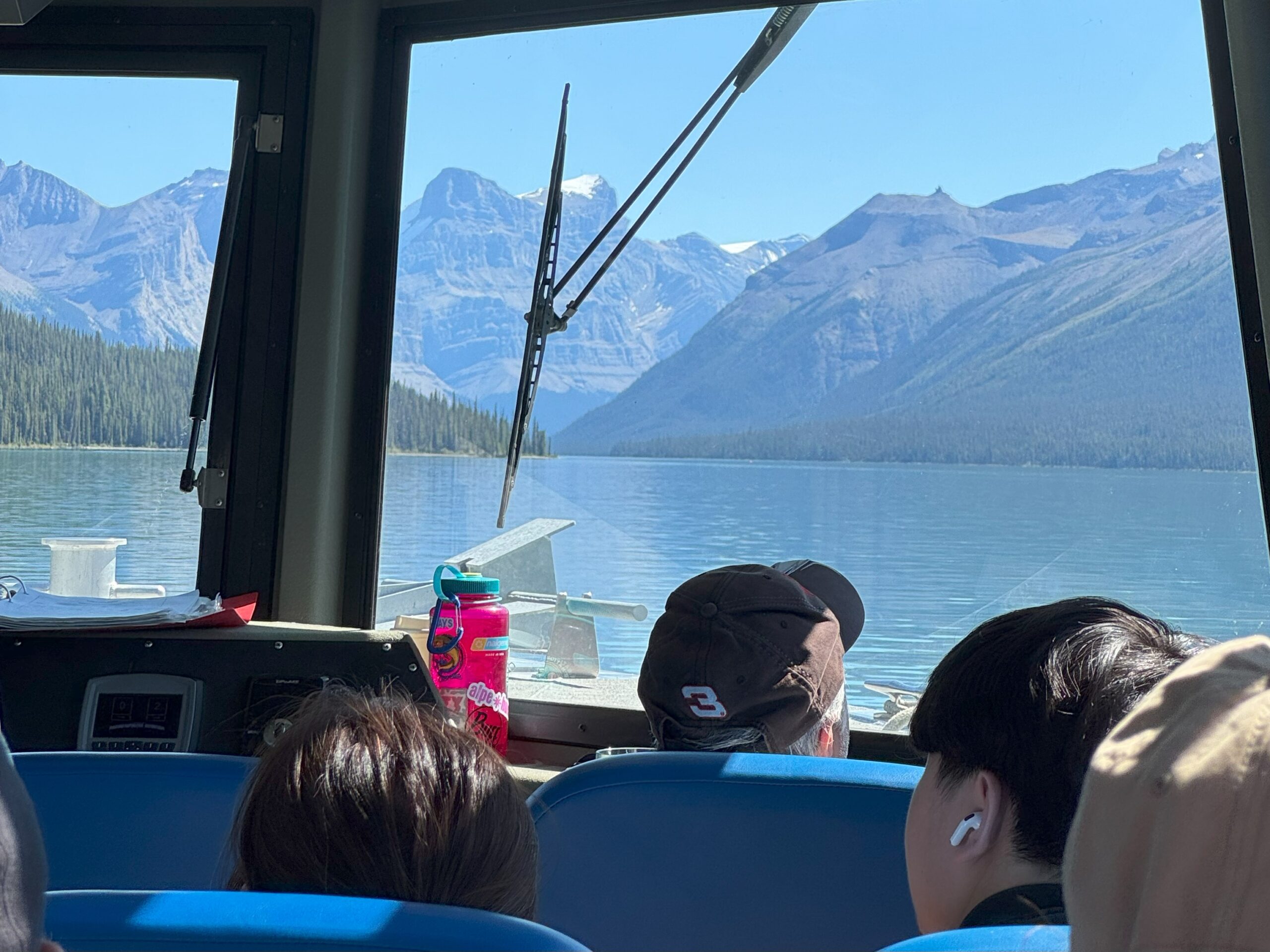 View of Maligne Lake and surrounding mountains from inside a tour boat in Jasper National Park, with passengers enjoying the scenic ride.