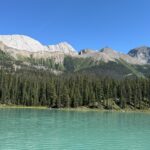 Turquoise waters of Maligne Lake with a backdrop of evergreen forest and rocky mountain peaks in Jasper National Park.