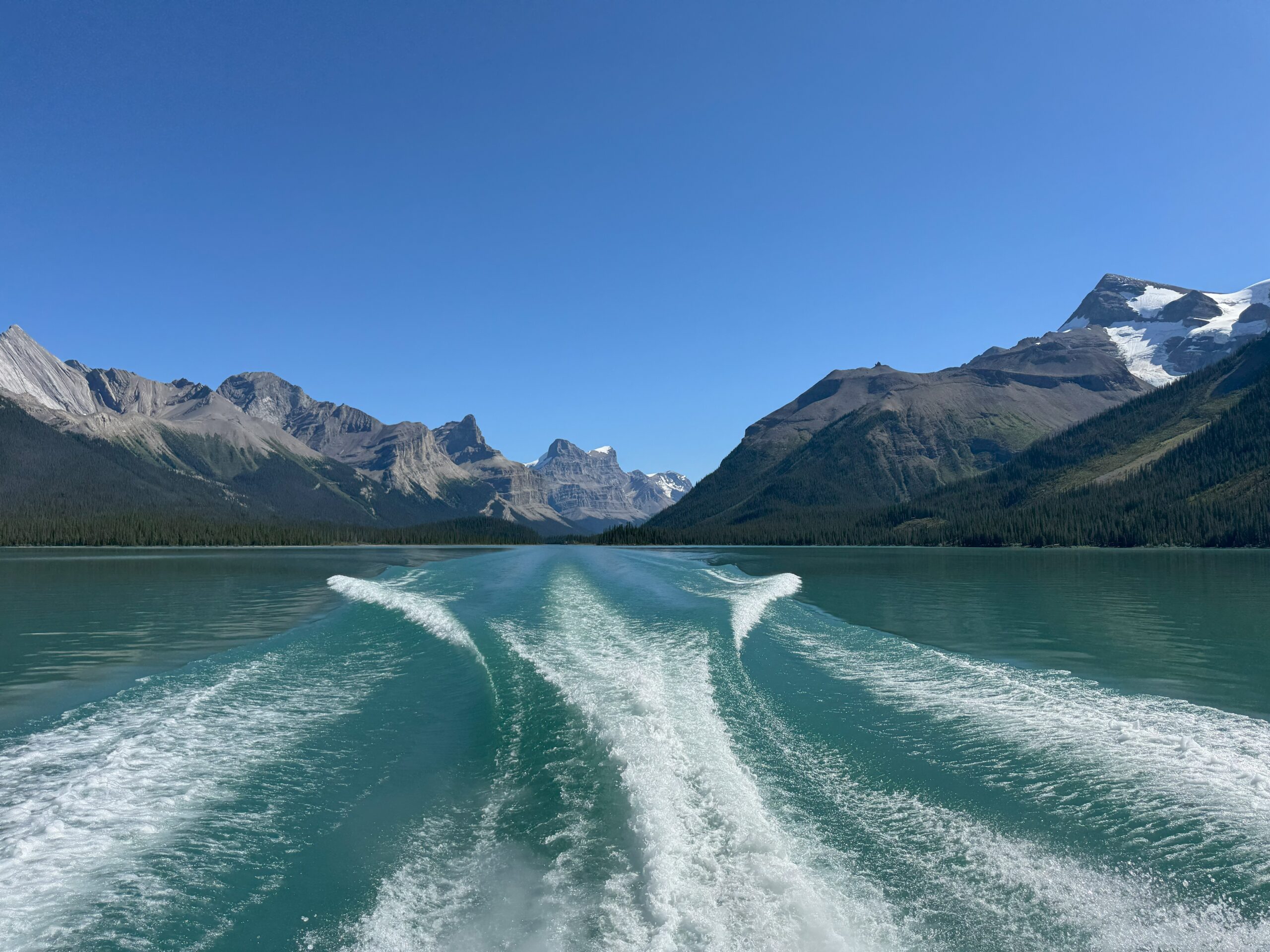 Wake of a boat on turquoise Maligne Lake with Rocky Mountains in the background, Jasper National Park, Alberta, Canada.