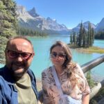 A couple taking a selfie on Spirit Island with Maligne Lake and the surrounding Rocky Mountains in Jasper National Park.