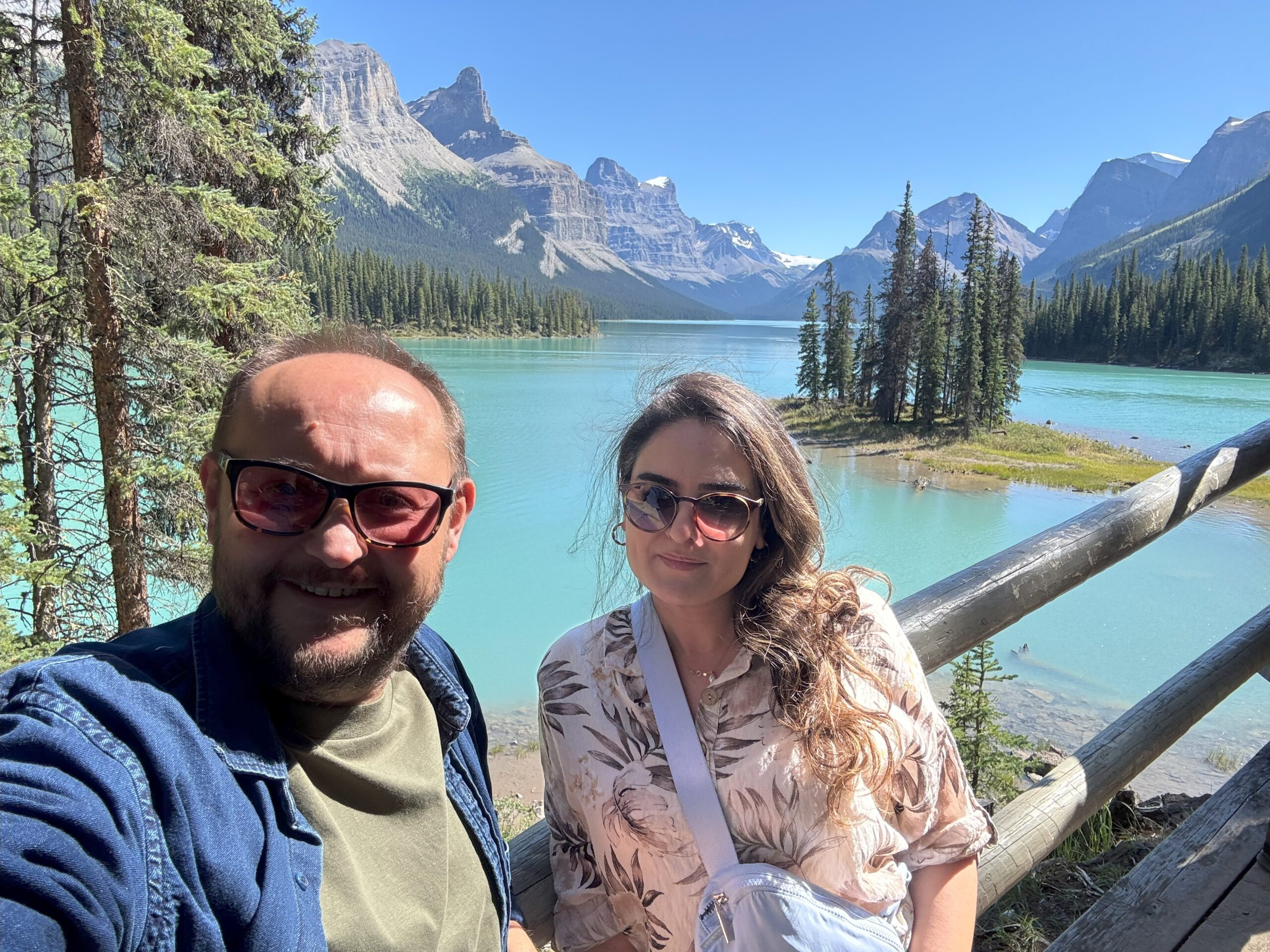 A couple taking a selfie on Spirit Island with Maligne Lake and the surrounding Rocky Mountains in Jasper National Park.