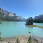 Scenic view of Spirit Island on Maligne Lake surrounded by turquoise water and towering Rocky Mountains in Jasper National Park.
