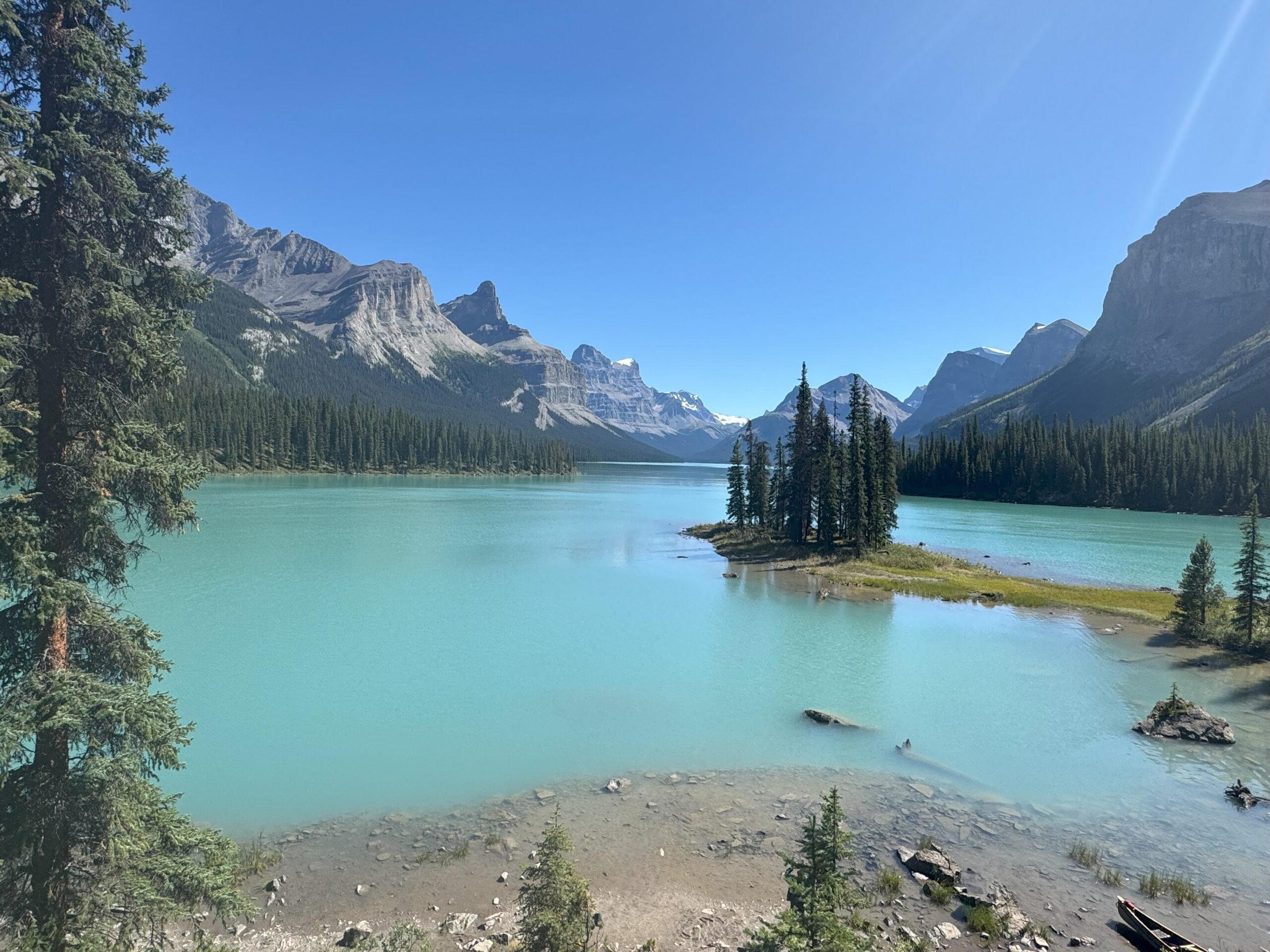Scenic view of Spirit Island on Maligne Lake surrounded by turquoise water and towering Rocky Mountains in Jasper National Park.