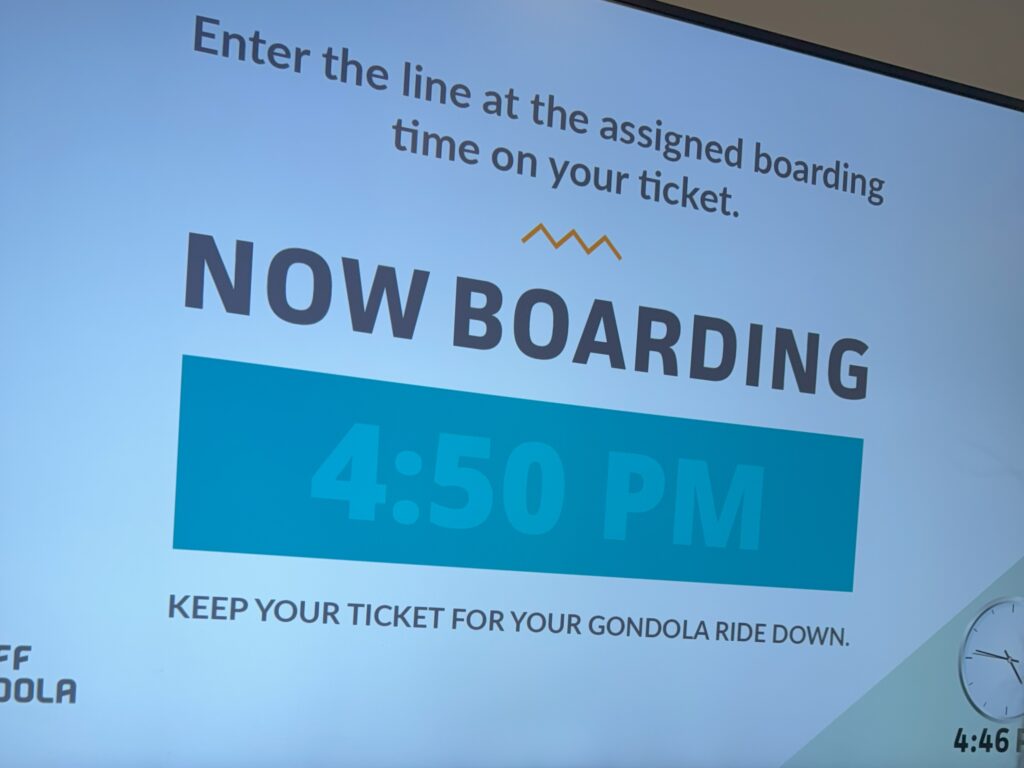 Banff Gondola Line Digital display showing the Banff Gondola boarding time of 4:50 PM with instructions for passengers.