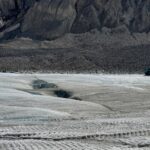 Görünür yarıklar, kayalık dağ yamaçları ve buz ve yol üzerinde bir buzul turu aracıyla Athabasca Buzulu'nun görünümü.