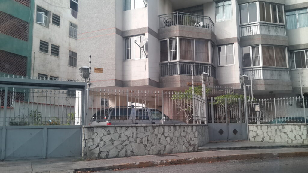 A residential building in Caracas with high metal fences and electrical wires installed on top for security.