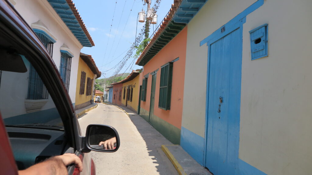 Güneşli bir günde arabadan çekilmiş, Choroni'deki (Venezuela) dar bir sokakta sıralanan renkli kolonyal evler.