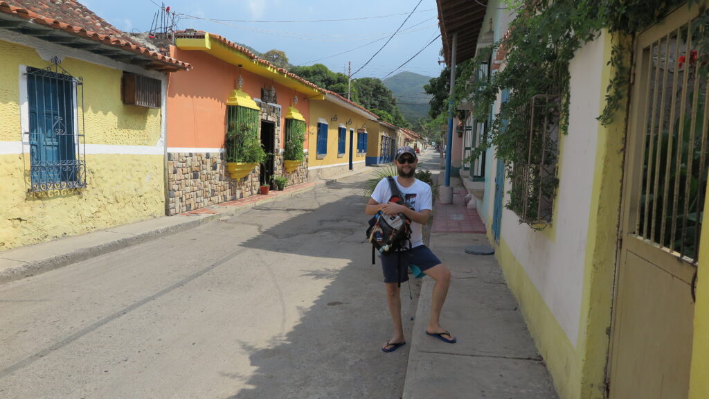 Choroni, Venezuela’da renkli kolonyal evlerin bulunduğu sakin ve güneşli bir sokakta duran bir gezgin.