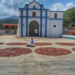 Venezuela'daki tarihi beyaz ve mavi renkli Iglesia de la Inmaculada Concepción kilisesinin önünde, kurumaya bırakılmış kakao çekirdekleri halkalarının arasında oturan bir gezgin.