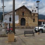 A historic colonial stone church in Girón with a white bell tower and a rustic facade.