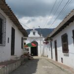 A narrow street leading to the white facade of Capilla de las Nieves in Girón.
