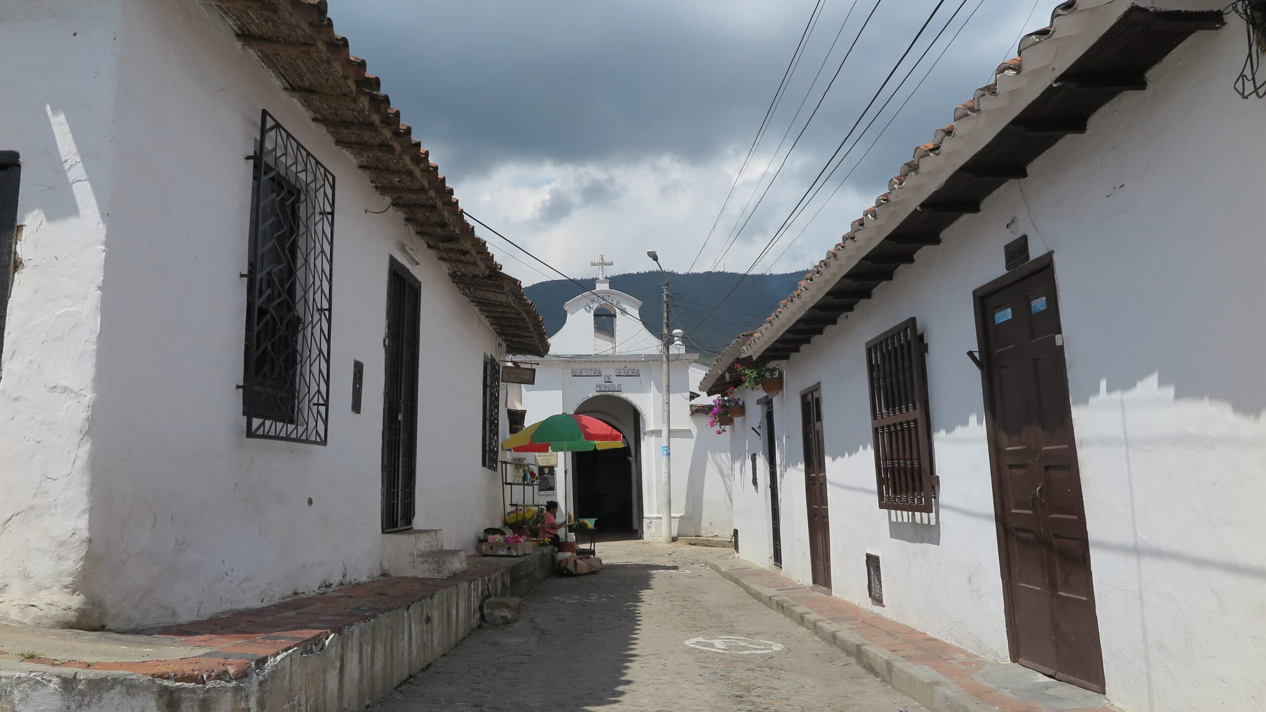 A narrow street leading to the white facade of Capilla de las Nieves in Girón.