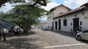 Kolombiya, Girón'da beyaz kolonyal binalar ve üniformalı öğrencilerin bulunduğu arnavut kaldırımlı bir sokak.