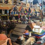 Colorful miniature Colombian house magnets and handcrafted wooden souvenirs on a display shelf at Plaza Central market in Bucaramanga.