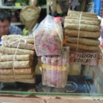 Hand-rolled Colombian cigars tied with string and packaged in plastic on a glass counter at Plaza Central market.
