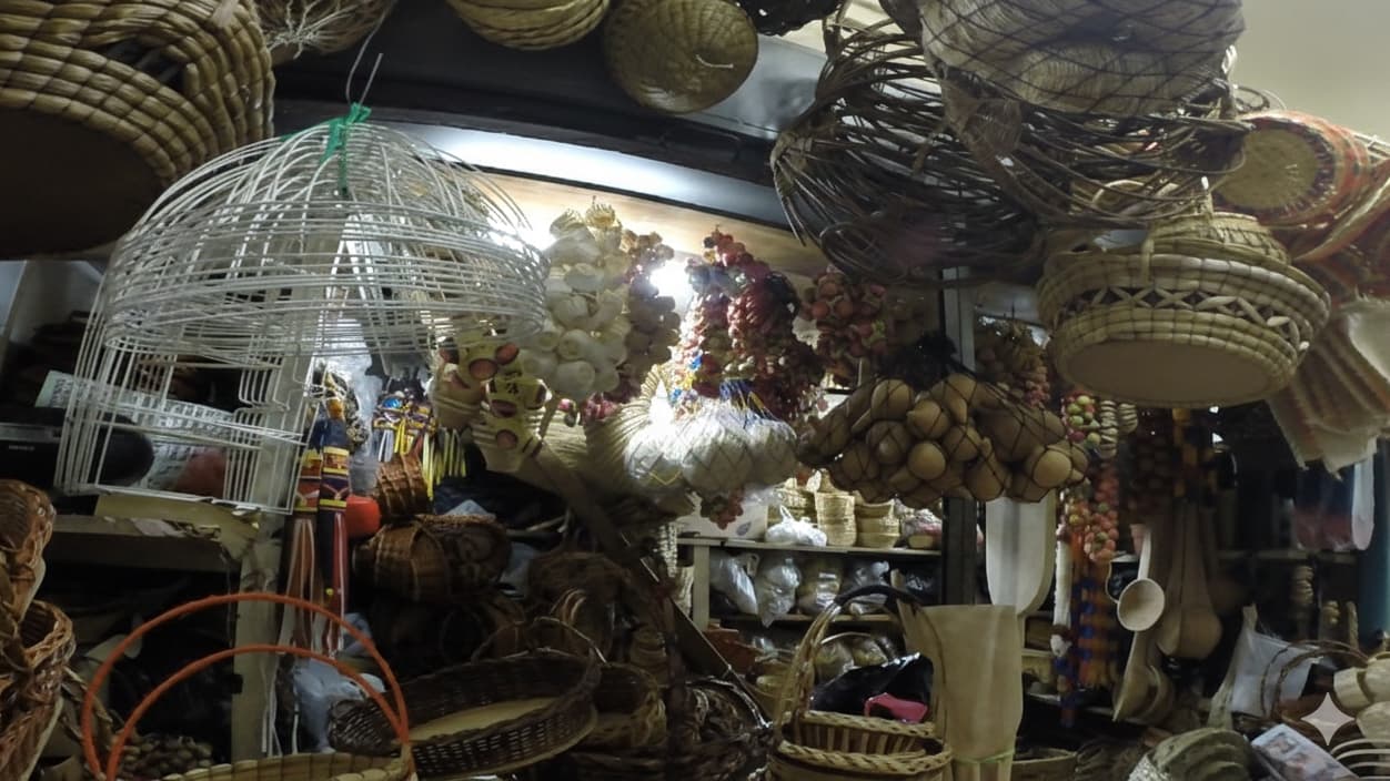 A variety of handcrafted wicker baskets and woven birdcages hanging in a dim market stall.