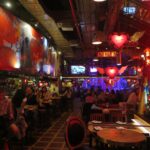 Colorful interior of Andrés Carne de Res (Andrés D.C.) in Bogotá, with neon heart signs, vibrant murals, warm red lighting, and guests dining at tables and the bar.