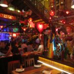 Interior of Andrés Carne de Res (Andrés D.C.) in Bogotá, filled with glowing red heart-shaped neon lights, eclectic décor, a colorful statue, and guests dining at wooden tables.