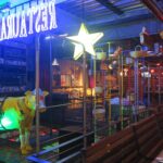 Vibrant interior of Andrés Carne de Res (Andrés D.C.) in Bogota featuring neon signs, a glowing yellow cow statue, and hanging baskets.