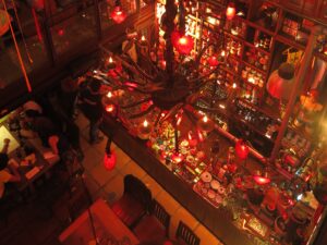 High-angle view of a crowded bar area in Andrés Carne de Res Bogota, featuring large red heart-shaped lanterns and an ornate chandelier.