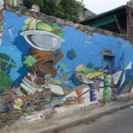 A colorful wall mural in Cartagena depicting a Palenquera woman carrying fruit on her head.