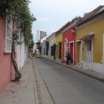 A row of small houses painted in various bright colors along a narrow street in Cartagena.