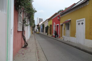 A row of small houses painted in various bright colors along a narrow street in Cartagena.