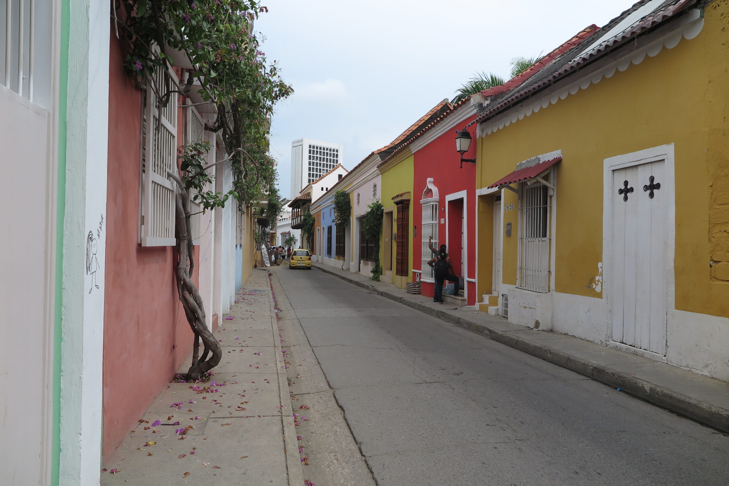 A row of small houses painted in various bright colors along a narrow street in Cartagena.