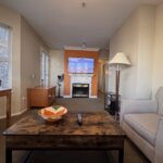 Spacious living room at Times Square Suites Hotel featuring a comfortable sofa, fireplace, and large windows.