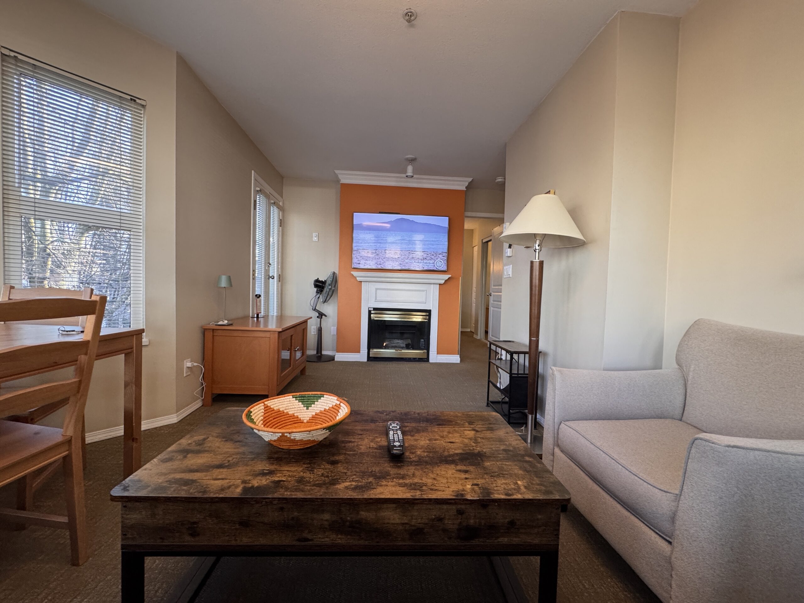 Spacious living room at Times Square Suites Hotel featuring a comfortable sofa, fireplace, and large windows.