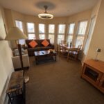 Spacious living room at Times Square Suites Hotel featuring a comfortable sofa, fireplace, and large windows.