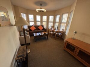 Spacious living room at Times Square Suites Hotel featuring a comfortable sofa, fireplace, and large windows.