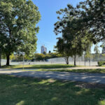 Tennis courts surrounded by trees with Vancouver downtown skyscrapers in the background at Kitsilano Beach Park.