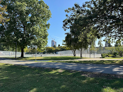 Tennis courts surrounded by trees with Vancouver downtown skyscrapers in the background at Kitsilano Beach Park.
