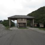 The main entrance gate and visitor center of the Cotacachi Cayapas Ecological Reserve in Ecuador, leading to Laguna de Cuicocha, with lush green mountains in the background.